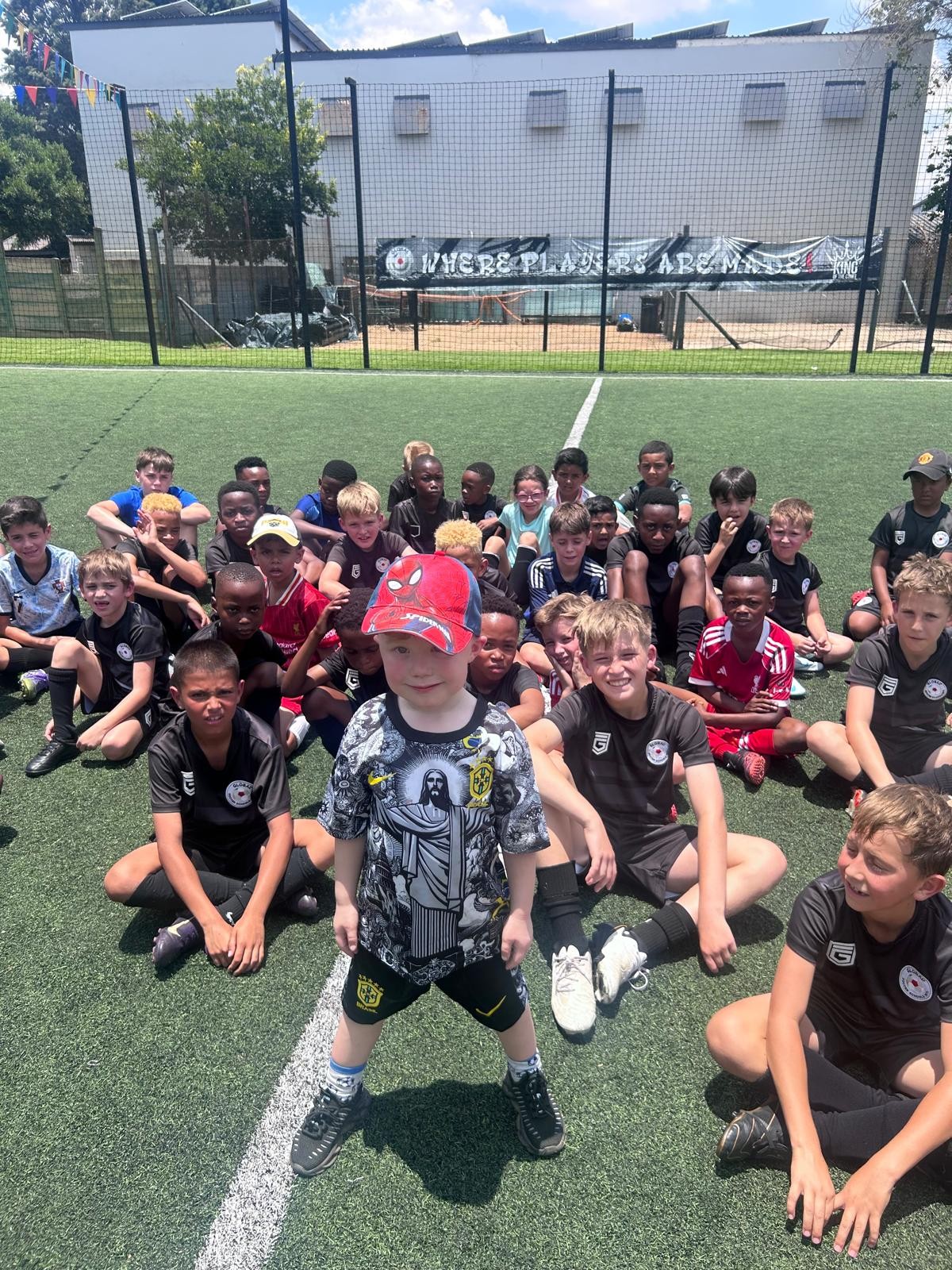Children and coaches gathered together on an outdoor football pitch